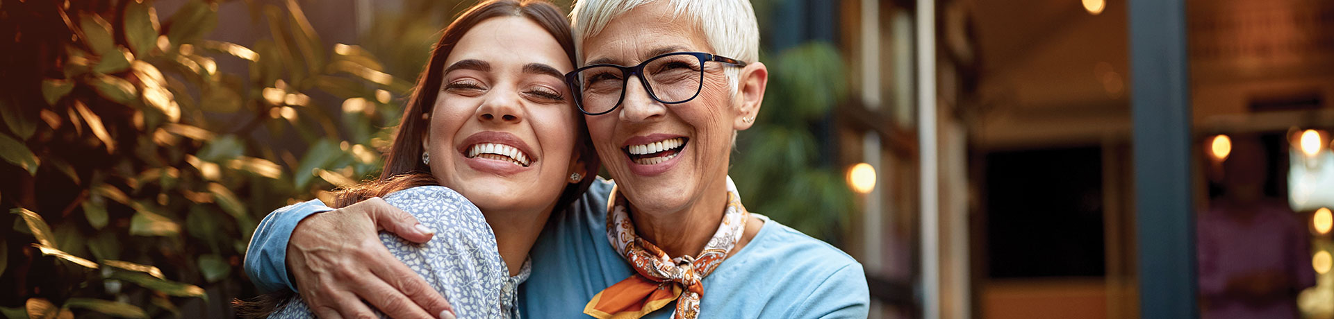 portrait of a senior mother and adult daughter, hugging, smiling.