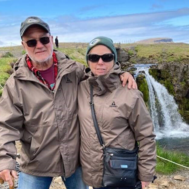 Marshall with his wife Shirley smiling and posing in front of a waterfall