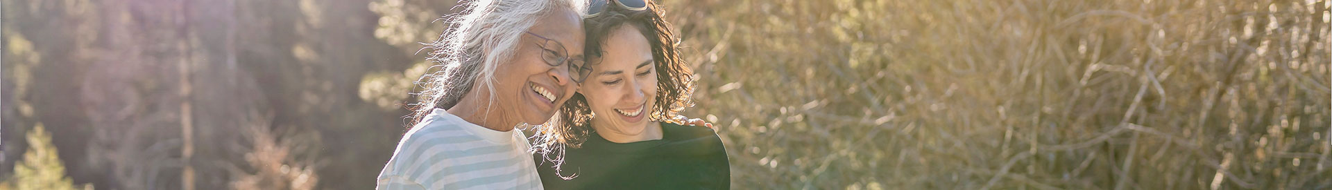 Mixed race young adult walking on a hiking trail with her Indian American senior mother