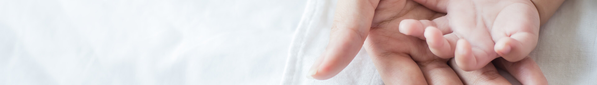 Baby's hand open on top of mother's palm