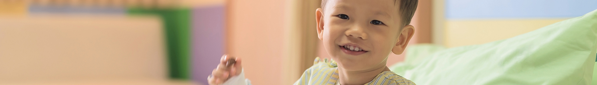 Smiling child with IV in hospital bed