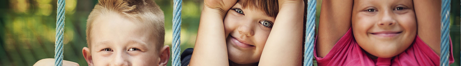 Smiling children hanging on a jungle gym rope