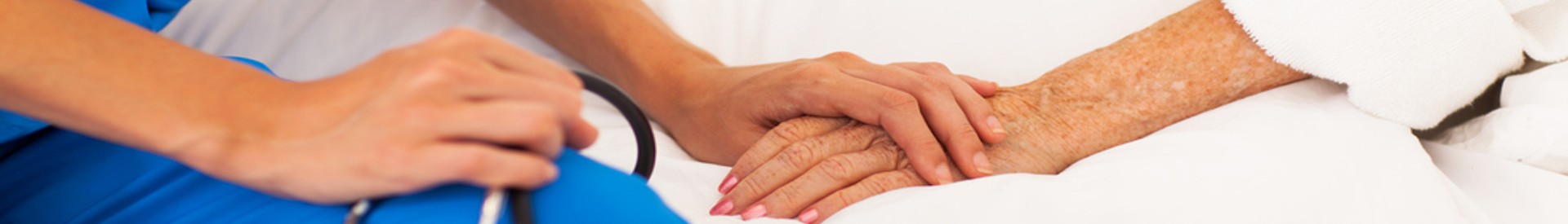 Nurse holding hand of wound patient who is laying in hospital bed